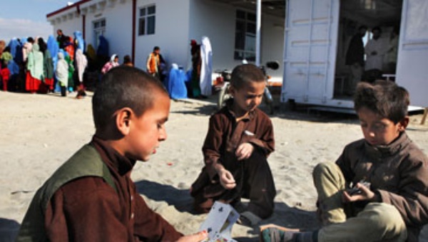 Children playing cards in front of the Italian hospital "Emergency"