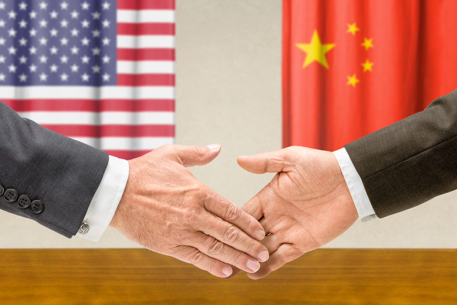 Image of two people shaking hands in front of the flags of the US and China, representing cooperation between the two countries