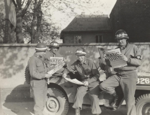 Photo of United States military policemen reading about the German surrender in World War 2